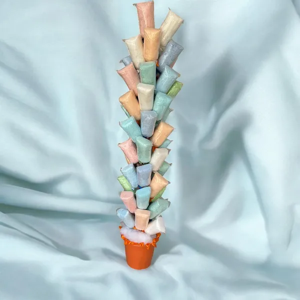 Árvore de algodão-doce em tons pastel, com vaso laranja sobre fundo azul claro