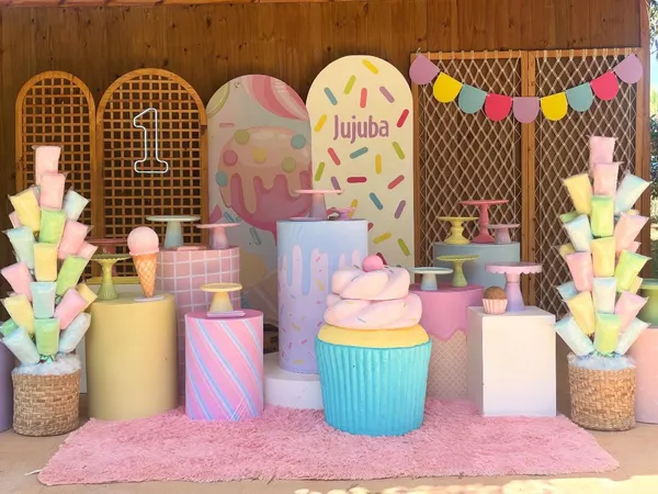 Duas árvores de algodão-doce rosa, amarelo, verde e azul nos lados de uma decoração de festa com tema de doces
