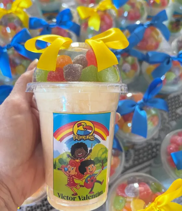 Copo de algodão-doce com balas coloridas, laço amarelo e rótulo do tema 3 Palavrinhas